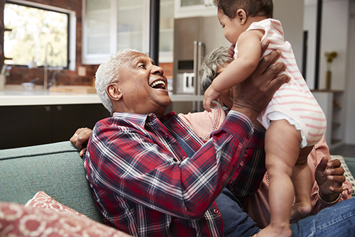 Elderly grandfather holding small infant up in the air to make him laugh