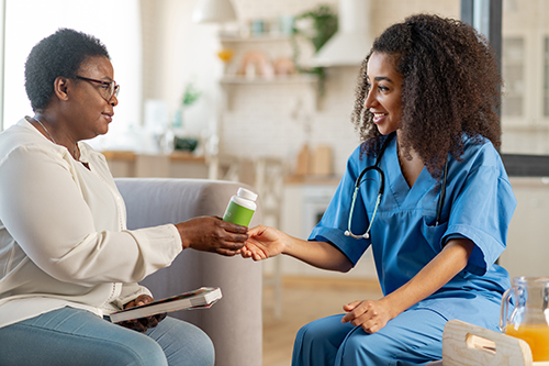 Nurse wearing stethoscope handing woman some medicine